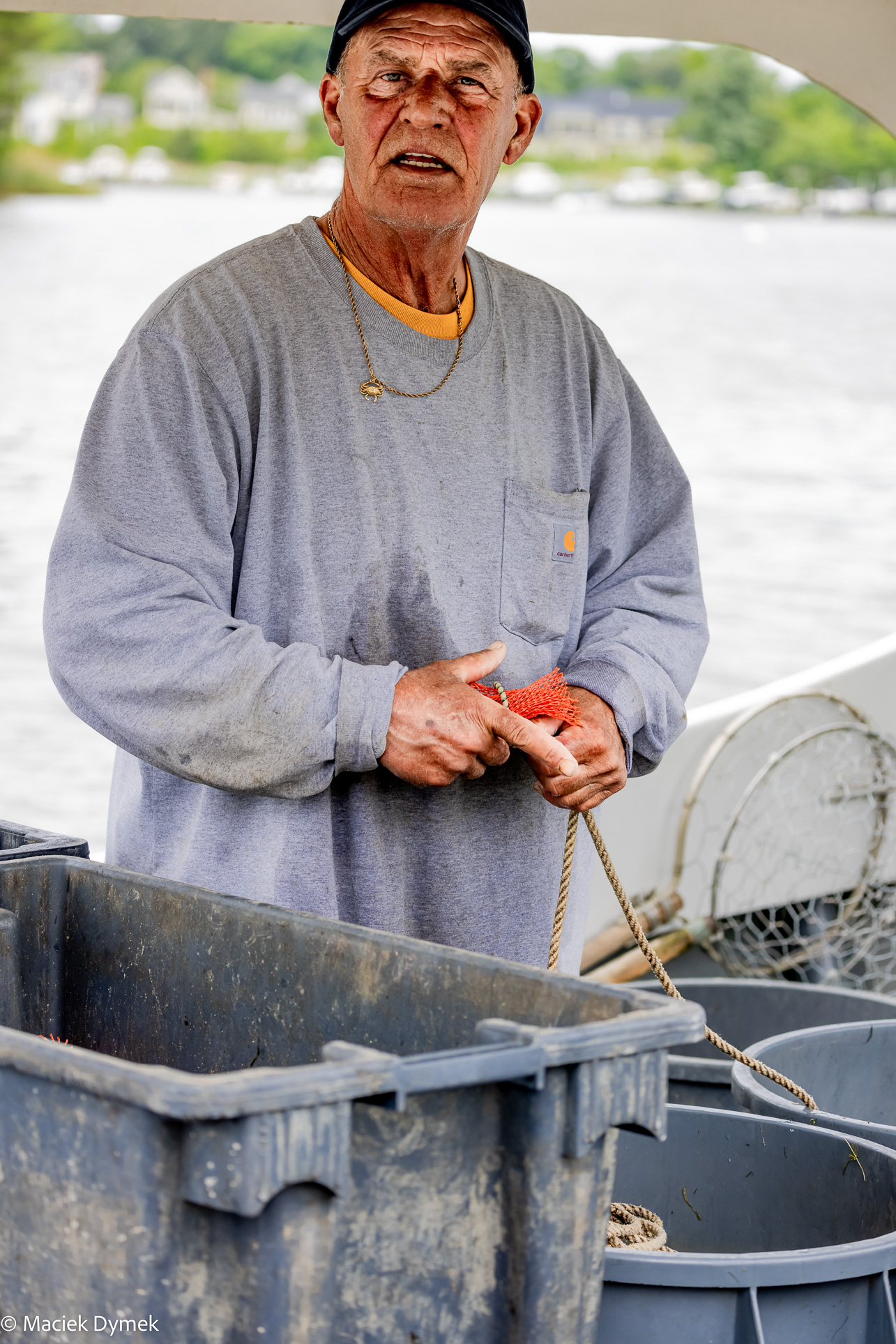 Documentary-style image of a hardworking Eastern Shore fisherman readying bait for the next day’s crabbing wet and sunburned, in work clothes on the Chesapeake Bay